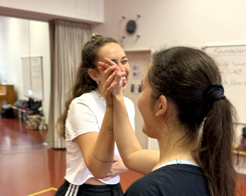 Zwei Frauen geben sich die Hand und lachen gemeinsam