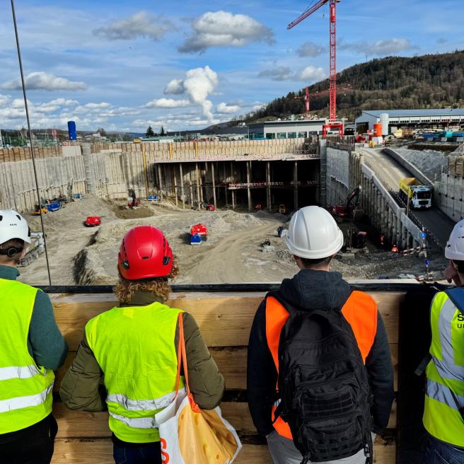 Baustelle im Hintergrund und vier Personen von hinten