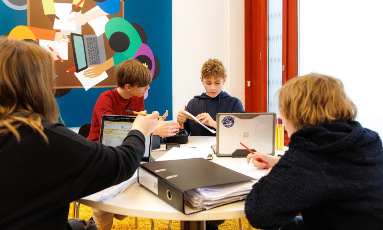 Kinder sitzen an einem Tisch und lernen miteinander am ipso! Haus des Lernens.