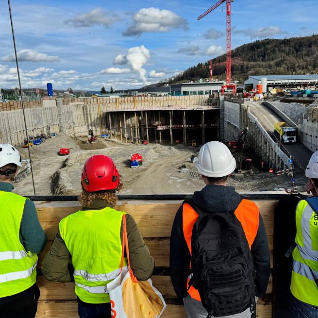 Baustelle im Hintergrund und vier Personen von hinten